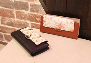 Close-up of printed floral patterns and golden metal buckles on long leather wallets