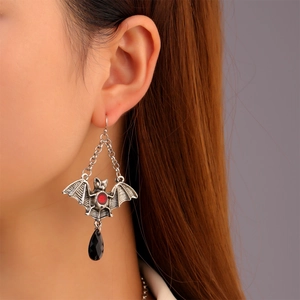 Gothic bat earring detail with red center and black teardrop pendant on a model