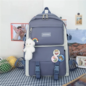Detail of Korean style student backpack with plush bear and rainbow charm on checkered desk