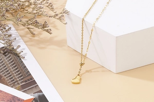 Elegant gold heart pendant necklace displayed on minimalist white geometric props