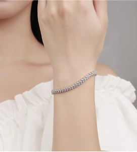 Close-up of a wavy silver tennis bracelet with moissanite stones on a woman wrist