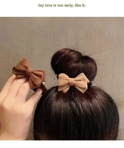 Detailed view of plush velvet bow hair scrunchies in brown and beige on a model's ponytail