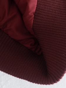 Detailed macro view of burgundy knit fabric texture and silky woven lining of the vest
