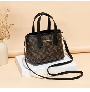 Detail der gemusterten Beuteltasche mit Doppelgriffen und Markenlogo auf Podest