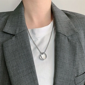 Close-up of a silver hip hop necklace with double ring pendant worn on a grey suit