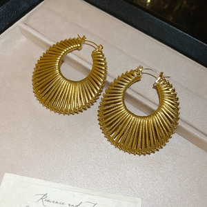 Détail de boucles d'oreilles créoles dorées texturées dans un écrin en velours