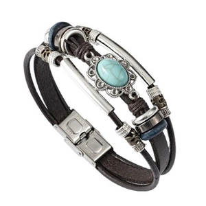 Detail of multi-layer leather bracelet with turquoise stone and patterned metal accents