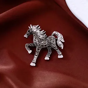 Vintage silver horse brooch with black rhinestones on elegant red satin background