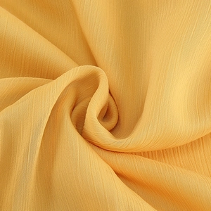 Vue détaillée montrant la texture plissée et le drapé doux du tissu en mousseline jaune