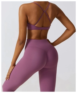 Detail of high-waisted yoga pants with V-shaped seam and cross back sports bra in purple
