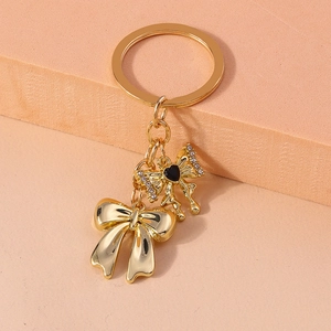 Detail of golden bow keychain with black enamel heart and sparkling rhinestones