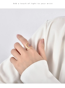 Detail of adjustable gold ring featuring a crescent moon and purple natural stone