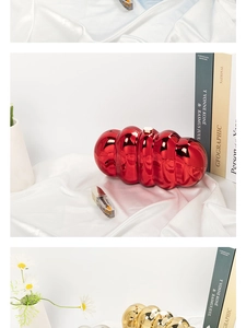 Detail of red and gold cloud-shaped acrylic clutch bags with metallic pleated texture