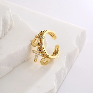 Detail of gold-plated open ring featuring coin charms and a sparkling cross pendant