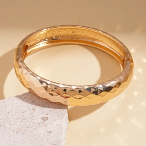Macro shot of gold hammered metal cuff bracelet on stone texture with artistic lighting