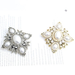 Detailed macro view of vintage diamond-shaped brooches with pearls and crystals in gold and silver
