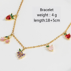 Detailed view of gold fruit charm bracelet with colorful cherry and peach zircons