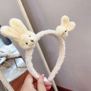 Detail of soft cream plush headband with two cute bunny ears held in a hand close-up