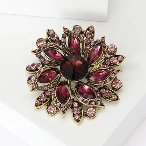 Close-up of vintage floral brooch with red and pink crystals on retro gold metal