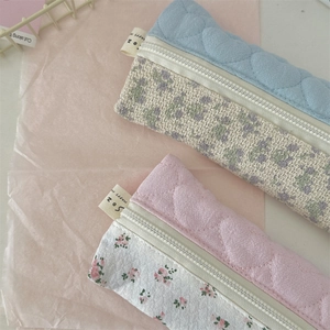 Detail van gewatteerd hartpatroon en bloemenstof van de etui met nylon ritssluiting