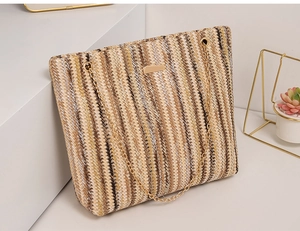 Close-up of vertical striped straw tote bag with golden metal chain and natural textures