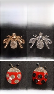 Detailed macro view of bee and ladybug alloy brooches with sparkling diamond inlay