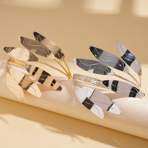 Detail of gold and silver multi-layer leaf arm cuffs with polished metallic finish