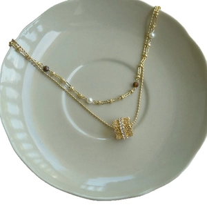 Double-layered gold necklace with zircon tiger eye pendant and pearl bead accents