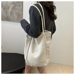 Close-up of off-white woven canvas tote bag shown as a shoulder bag on model for daily commuting