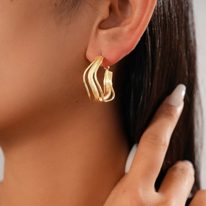 Detail of golden U-shaped textured earrings worn by model with matte and polished finish