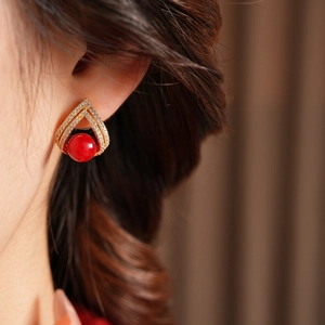 Gros plan sur boucle d'oreille triangle plaquée or 18k avec perle rouge et zircon brillant