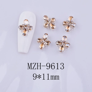 Detail view of 9x11mm amber floral alloy nail gems shown on a white manicure tip