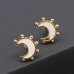 Détail des boucles d'oreilles croissant de lune plaqué or avec émail blanc et bord perlé