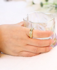Close-up of golden stainless steel ring with micro-paved crystals worn on finger