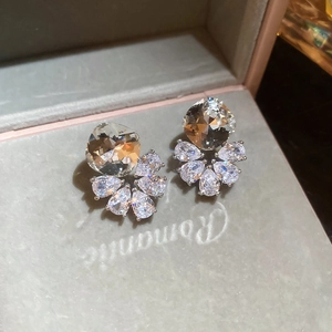 Macro shot of silver stud earrings with cushion-cut crystals and pear-shaped accents
