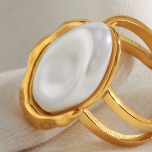 Macro detail of multi-layered 18K gold-plated ring with baroque pearl on beige velvet