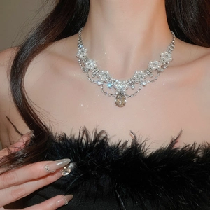 Close-up of diamond floral necklace with water drop pendant on a model in black attire