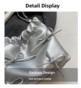 Close-up of silver pleated bucket bag with metallic bows and chain strap details