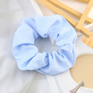 Light blue stretchy velvet hair scrunchie with sparkling rhinestones on fabric surface