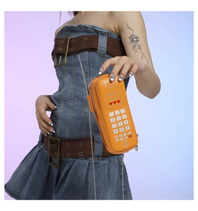 Détail du sac à bandoulière orange en forme de téléphone rétro avec chaîne métal