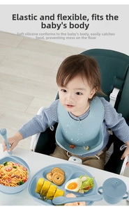 Asian baby using a blue silicone feeding set with a bib and suction plate on a high chair