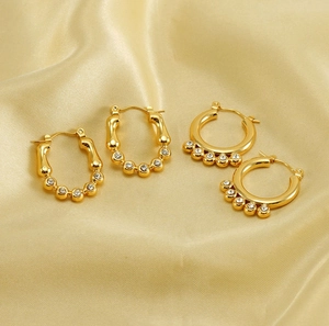 Close-up of 18K gold plated hoop earrings with inlaid zircons on champagne silk fabric