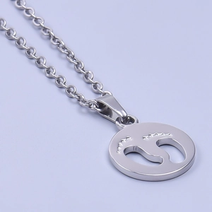 Macro shot of silver stainless steel necklace featuring a hollow baby footprint pendant