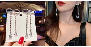 Detail of silver long tassel earrings with crystal bow and teardrop stones on model