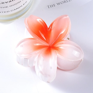 Close-up of pink frangipani hair claw clip made of glossy resin with metal spring