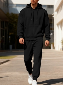 Outdoor shot of men's black hooded fleece tracksuit featuring ribbed cuffs and zipper detail