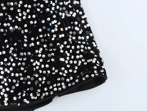 Detailed macro view of silver sequins on black velvet fabric for party dresses