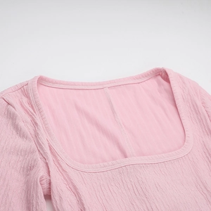 Detailed view of pink square neck dress with elegant vertical ribbed texture and fabric pleats