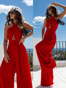 Detail of red halter neck jumpsuit featuring waist cut-out and wide leg silhouette