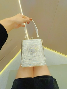 Macro view of crystal rhinestone flower and geometric beadwork on white evening bag